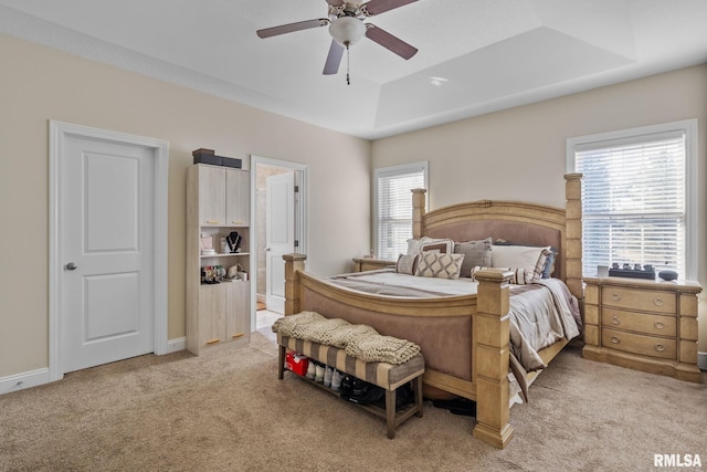 bedroom with light carpet, a ceiling fan, a raised ceiling, and baseboards