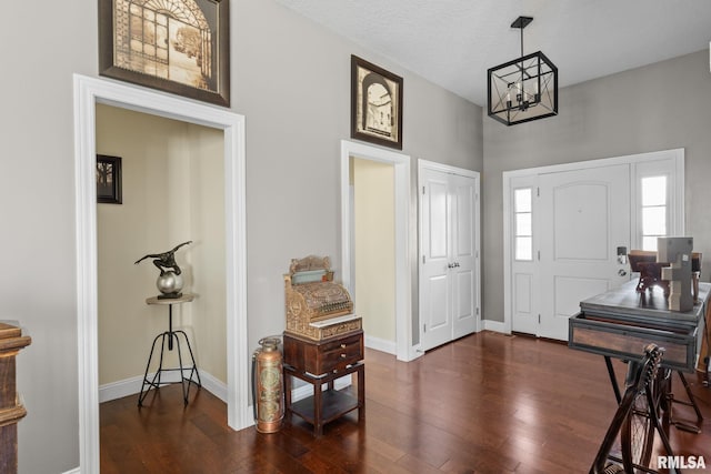 foyer entrance with baseboards, dark wood-style flooring, and a chandelier