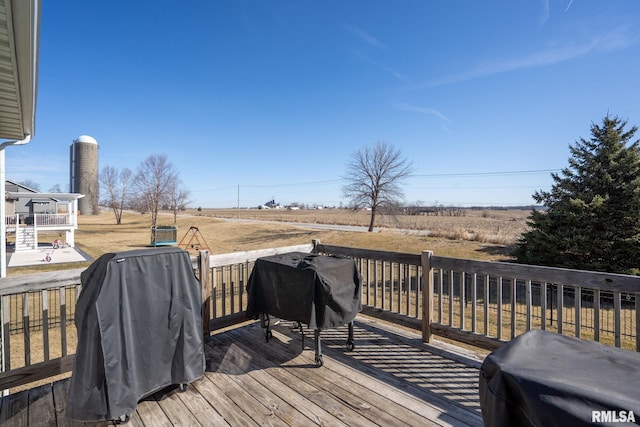 wooden deck with a rural view and a grill