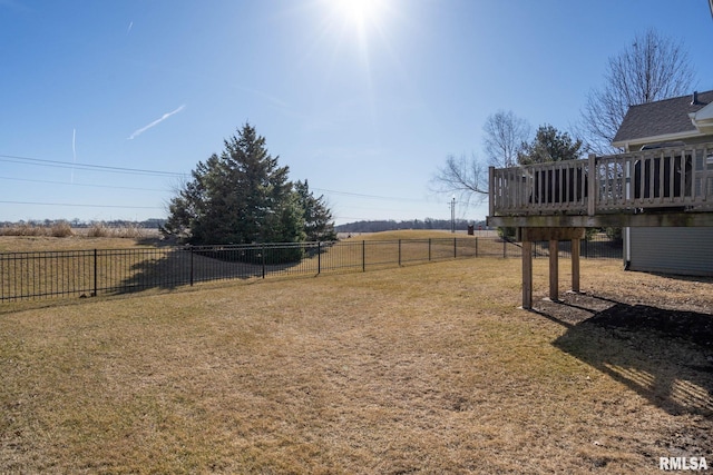 view of yard with a rural view, a deck, and fence