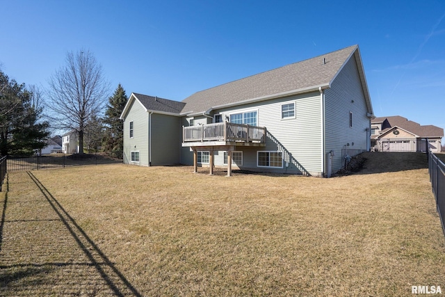 rear view of house featuring a shingled roof, a yard, a fenced backyard, and a wooden deck