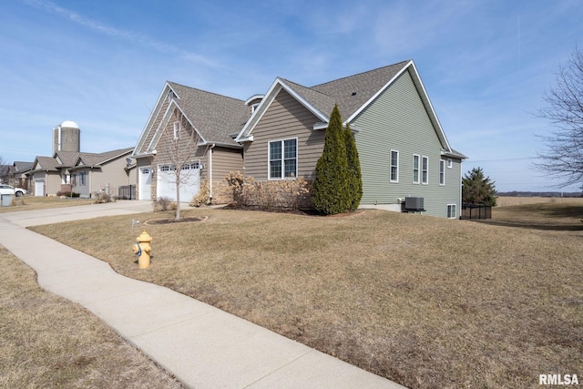 view of side of home featuring a lawn, roof with shingles, concrete driveway, a garage, and central AC unit