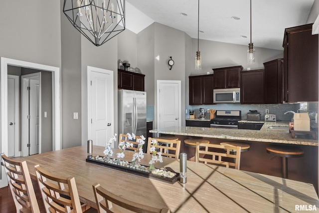 kitchen with dark brown cabinetry, light stone countertops, appliances with stainless steel finishes, and a sink