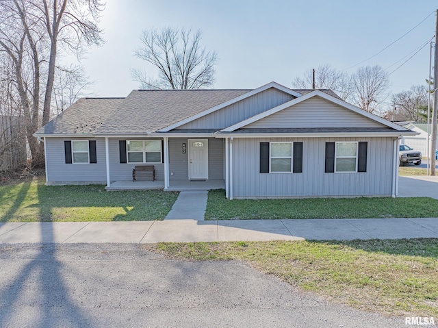 view of front facade featuring covered porch, a front yard, and roof with shingles