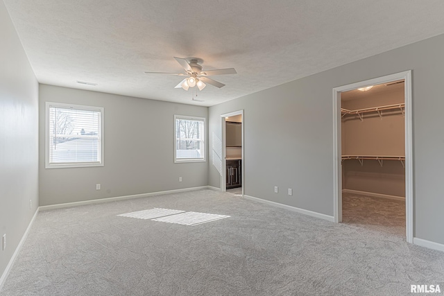 unfurnished bedroom featuring a spacious closet, carpet flooring, a textured ceiling, and baseboards