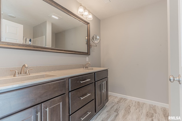 full bathroom with double vanity, wood finished floors, baseboards, and a sink