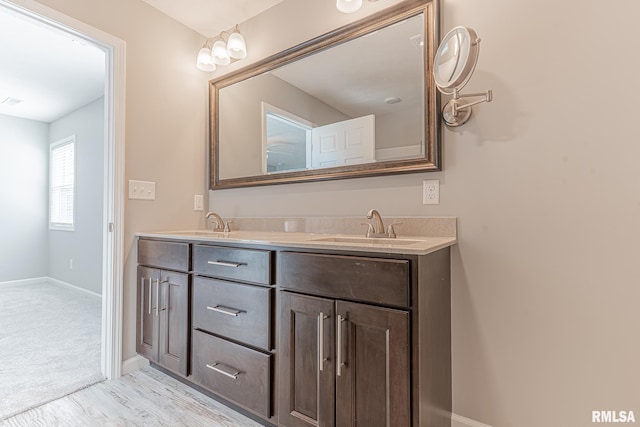 full bath with double vanity, baseboards, and a sink