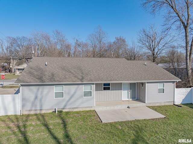 rear view of house featuring a yard, fence, a shingled roof, and a patio area