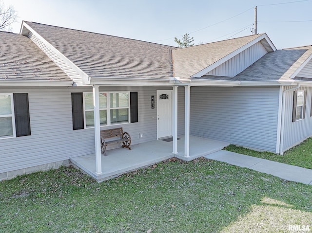 property entrance with a lawn and a shingled roof