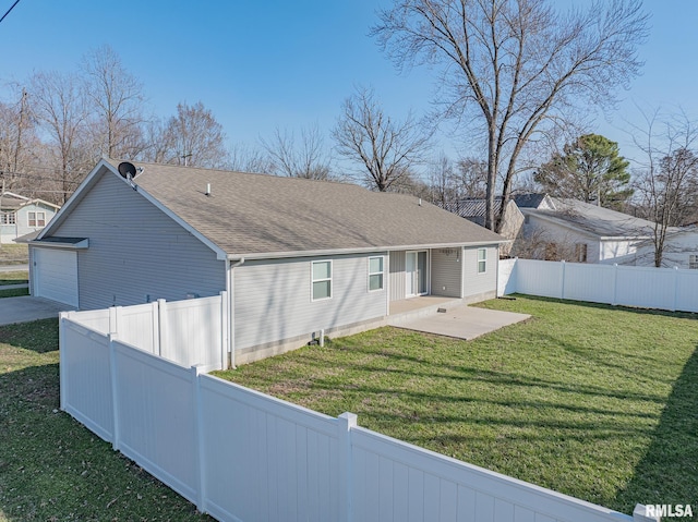 rear view of property with a lawn, a garage, a fenced backyard, and a shingled roof