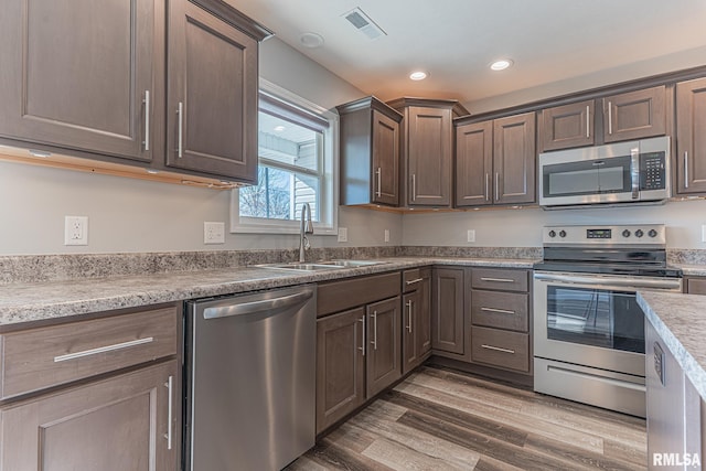 kitchen featuring wood finished floors, visible vents, recessed lighting, a sink, and stainless steel appliances