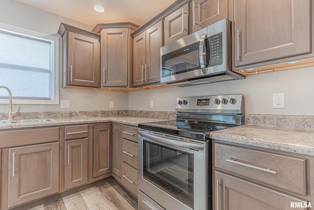 kitchen featuring light wood-style flooring, recessed lighting, a sink, stainless steel appliances, and light countertops