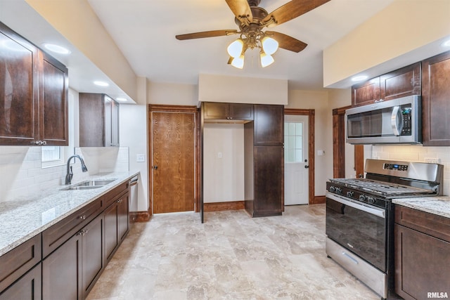 kitchen with light stone counters, baseboards, a sink, stainless steel appliances, and tasteful backsplash