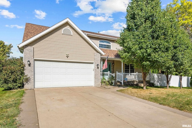 traditional home with covered porch, concrete driveway, a front yard, a garage, and brick siding