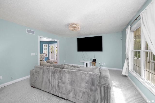 living room with visible vents, a textured ceiling, french doors, carpet flooring, and baseboards