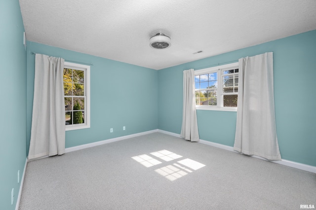 unfurnished room with carpet flooring, visible vents, baseboards, and a textured ceiling