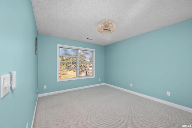 spare room featuring visible vents, baseboards, a textured ceiling, and carpet flooring