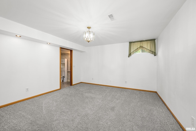 carpeted empty room with a notable chandelier, visible vents, and baseboards