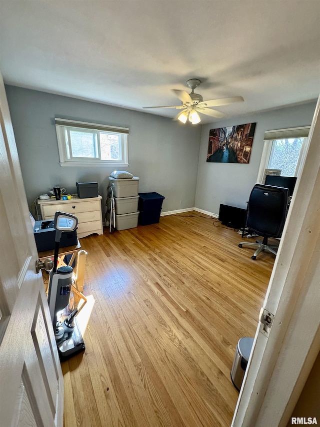 home office with a wealth of natural light, a ceiling fan, baseboards, and wood finished floors