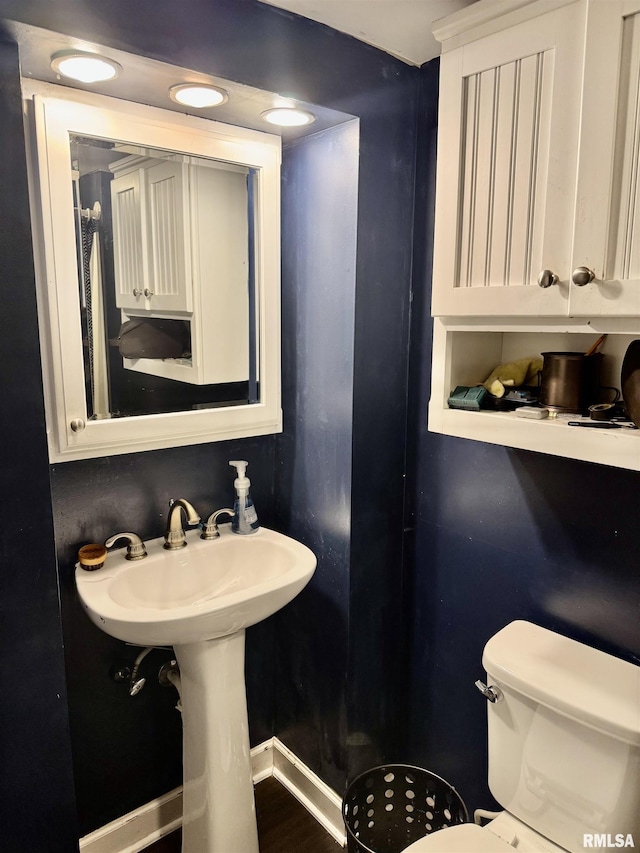 bathroom with a sink, baseboards, and toilet