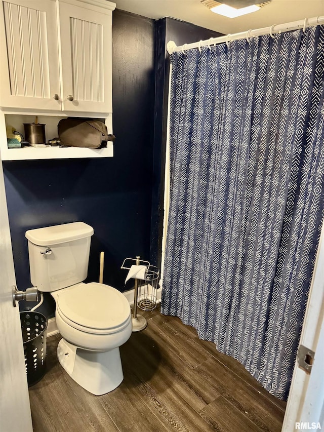 full bath featuring curtained shower, toilet, and wood finished floors