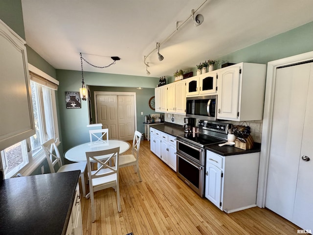 kitchen featuring dark countertops, decorative backsplash, light wood finished floors, and stainless steel appliances