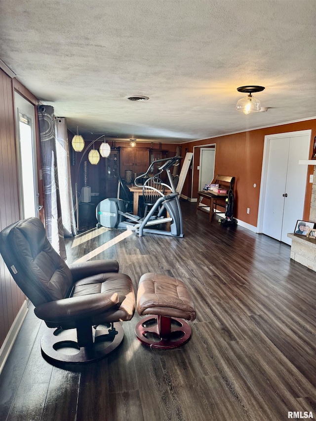 living area with baseboards, wood finished floors, visible vents, and a textured ceiling