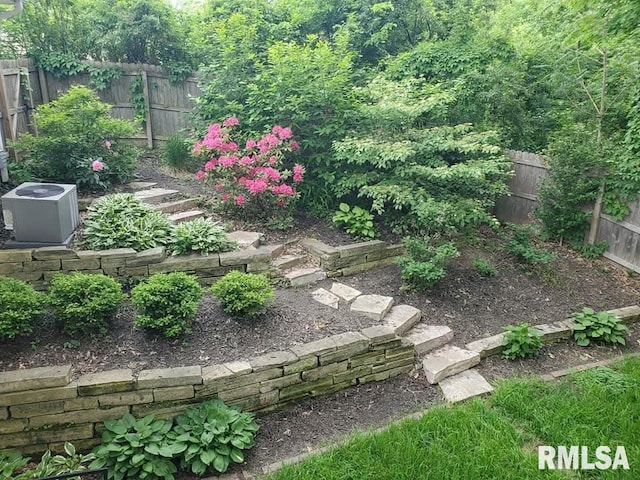 view of yard with a garden, cooling unit, and fence private yard