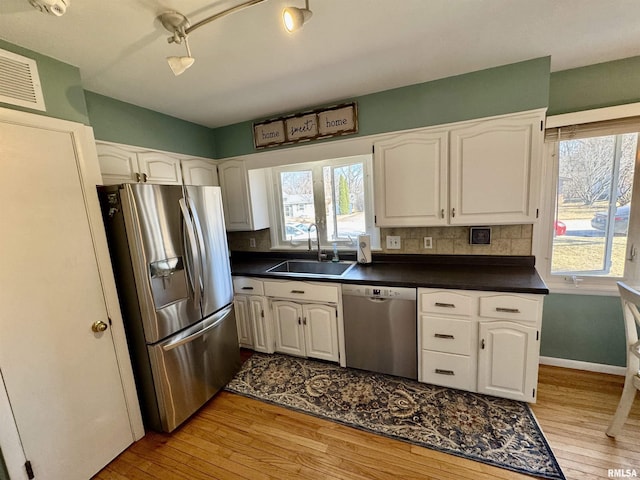 kitchen featuring a sink, dark countertops, white cabinetry, and stainless steel appliances