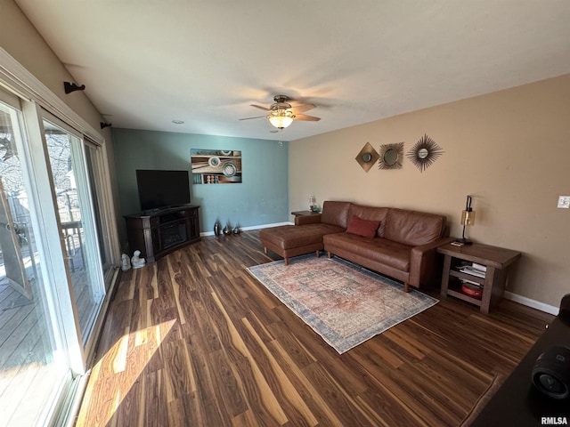 living room with ceiling fan, baseboards, and wood finished floors