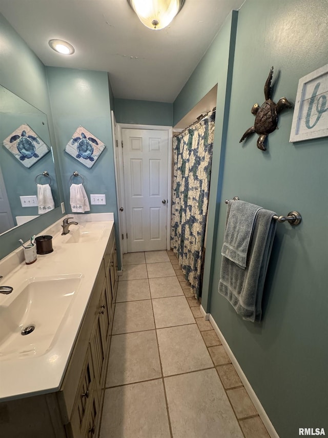 bathroom featuring tile patterned floors, double vanity, baseboards, and a sink