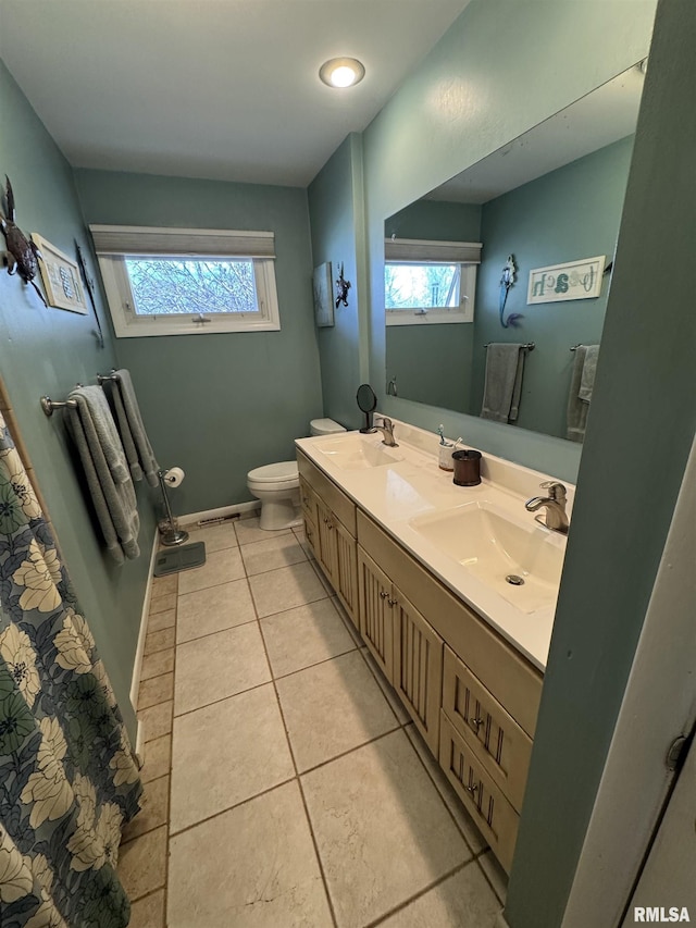 full bath featuring tile patterned floors, toilet, double vanity, and a sink