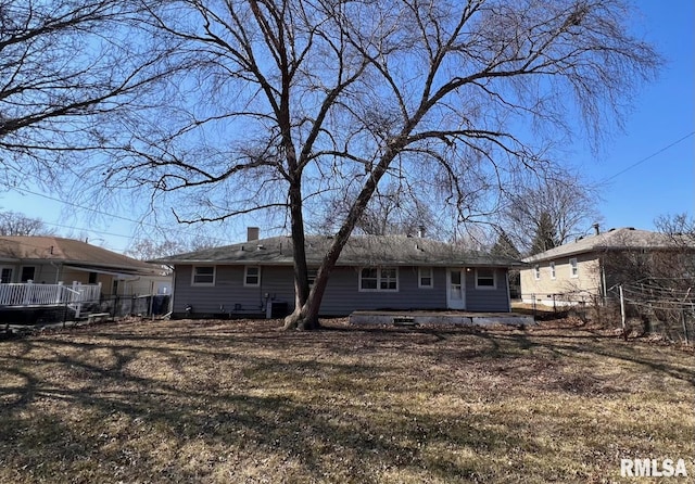 back of house with a chimney and fence