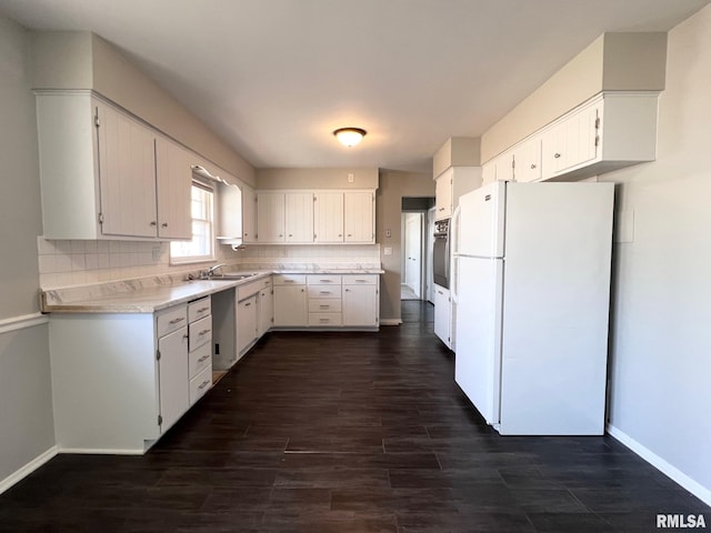 kitchen featuring baseboards, dark wood finished floors, light countertops, decorative backsplash, and freestanding refrigerator