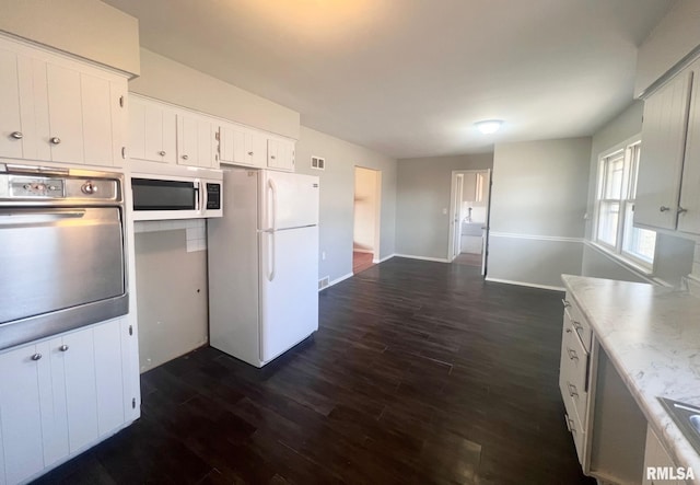 kitchen with visible vents, dark wood-type flooring, light countertops, white cabinets, and white appliances