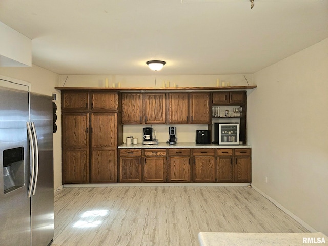 kitchen with light countertops, baseboards, stainless steel refrigerator with ice dispenser, and light wood finished floors