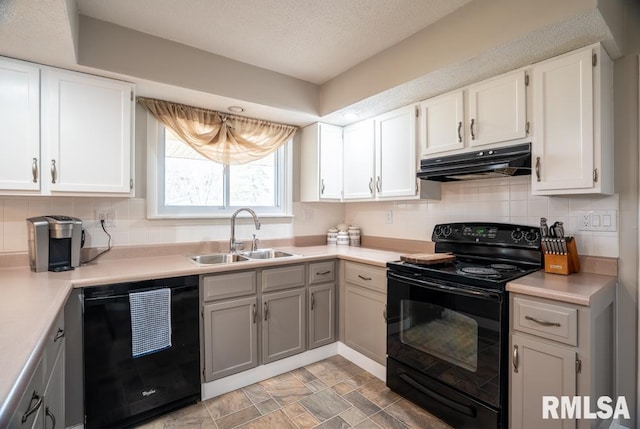 kitchen with black appliances, tasteful backsplash, under cabinet range hood, and a sink