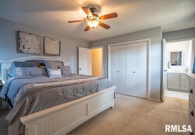 bedroom featuring a ceiling fan, a sink, a closet, a textured ceiling, and light colored carpet