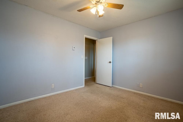 empty room featuring light colored carpet, baseboards, and a ceiling fan