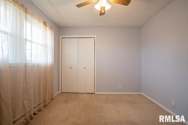 unfurnished bedroom with a closet, baseboards, a ceiling fan, and carpet flooring