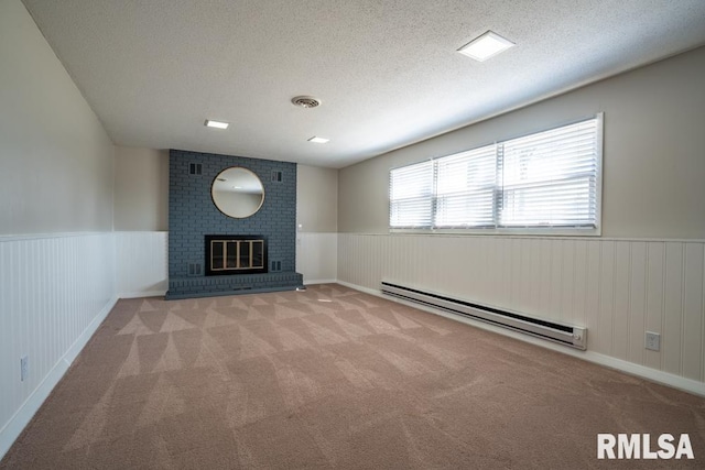 unfurnished living room with visible vents, a wainscoted wall, a textured ceiling, carpet flooring, and baseboard heating