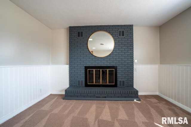 interior details featuring a fireplace, visible vents, carpet, and a wainscoted wall