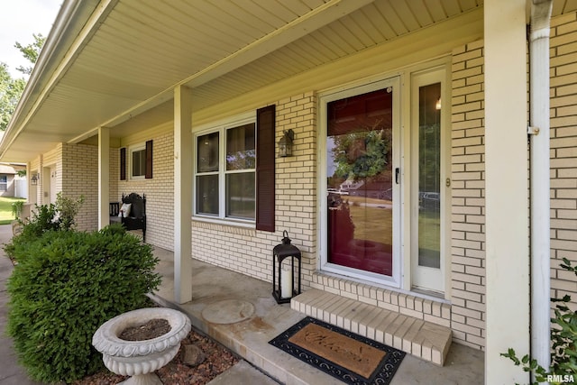 doorway to property featuring brick siding and covered porch