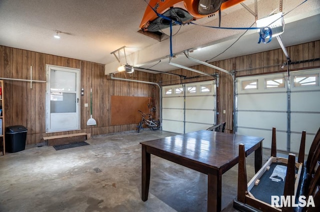 garage with wood walls and a garage door opener