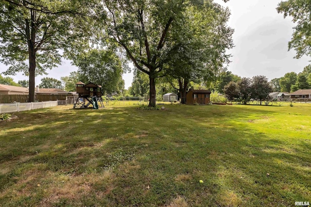 view of yard featuring an outdoor structure, a playground, and fence