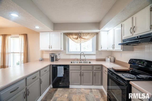 kitchen featuring black appliances, a sink, under cabinet range hood, tasteful backsplash, and light countertops