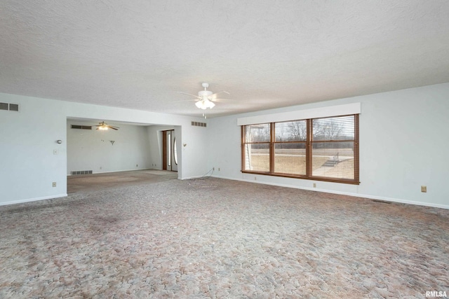 carpeted spare room featuring visible vents, a textured ceiling, and ceiling fan