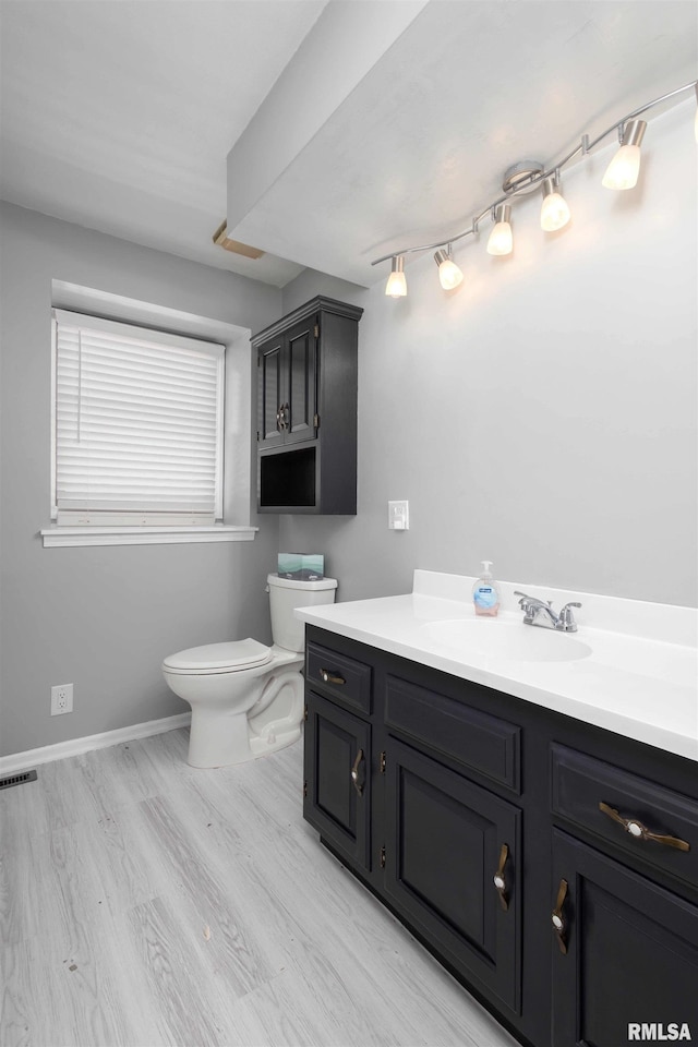 bathroom featuring vanity, wood finished floors, visible vents, baseboards, and toilet