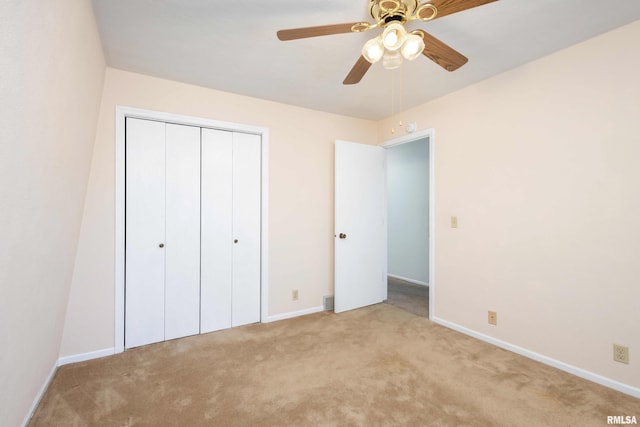 unfurnished bedroom with a closet, light colored carpet, and baseboards