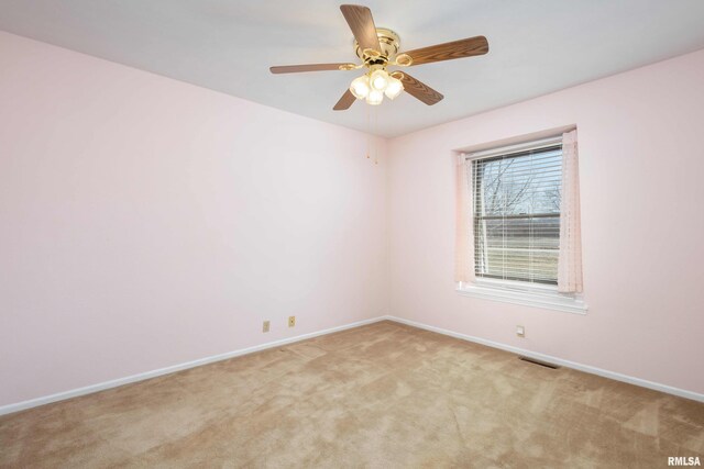 spare room featuring light carpet, visible vents, ceiling fan, and baseboards